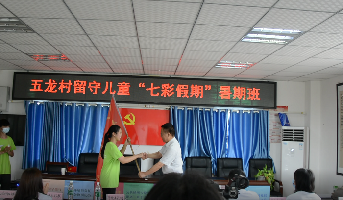 \\tsclient\G\稿件\2020.7.16小我融入大我，青春献给祖国；决战脱贫攻坚，投身强国伟业——眉山药科职业学院2020年“三下乡”之关爱丹棱县五龙村留守儿童“七彩假期”暑假班正式开班\图为文主任为夏辰小队授旗.png